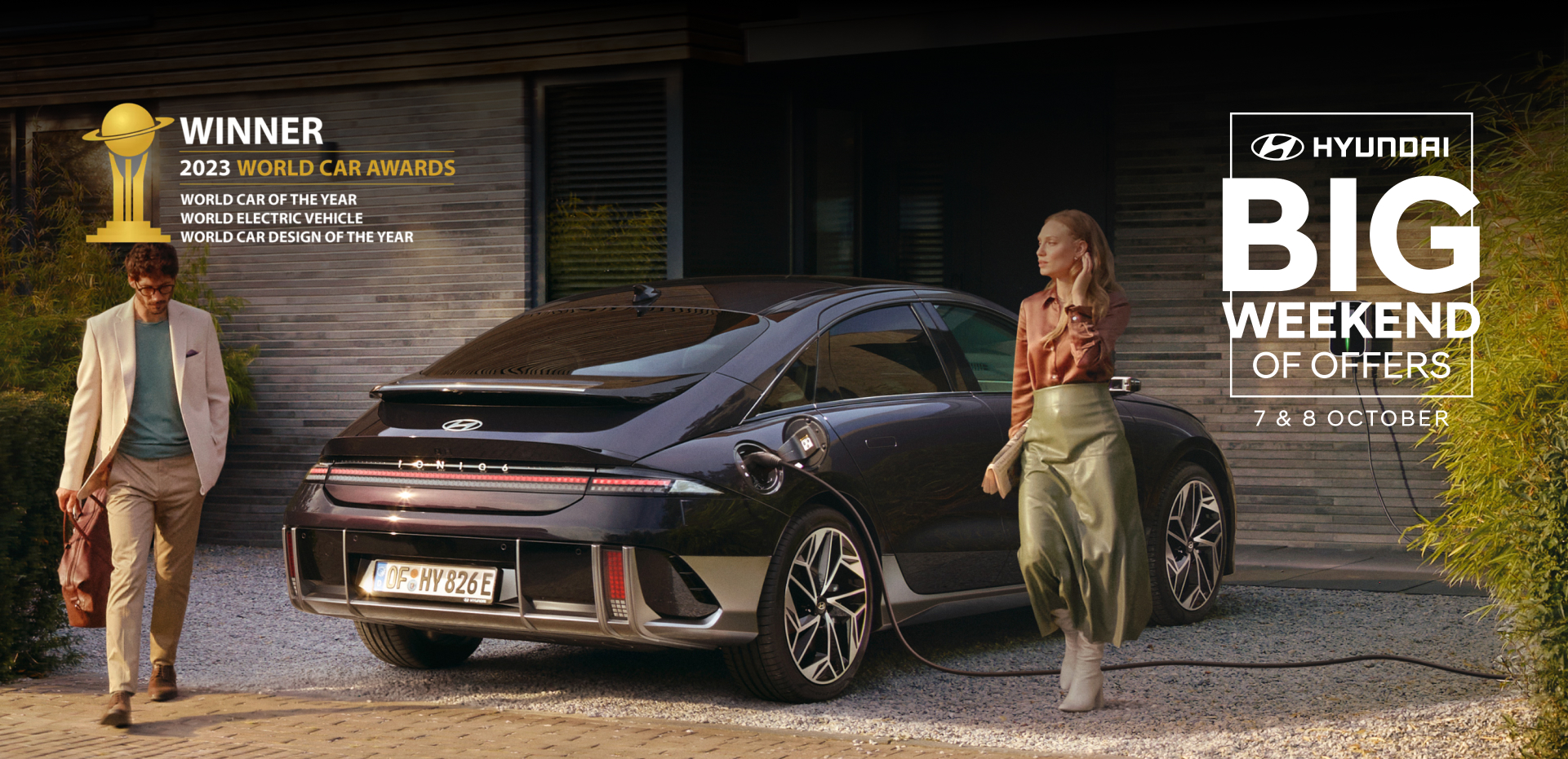 The all-electric Hyundai IONIQ 6 charging in a city with a man leaning on it with an ice cream.